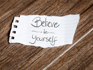 Torn piece of paper with "Believe in yourself" written on it